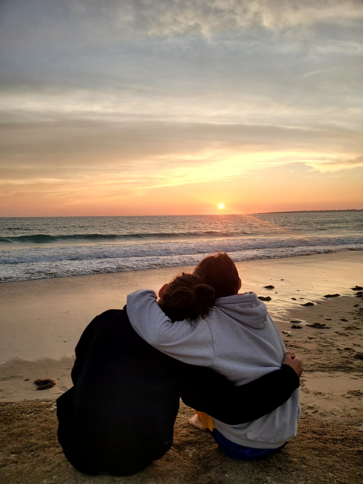 Two people watching the sunset at the ocean
