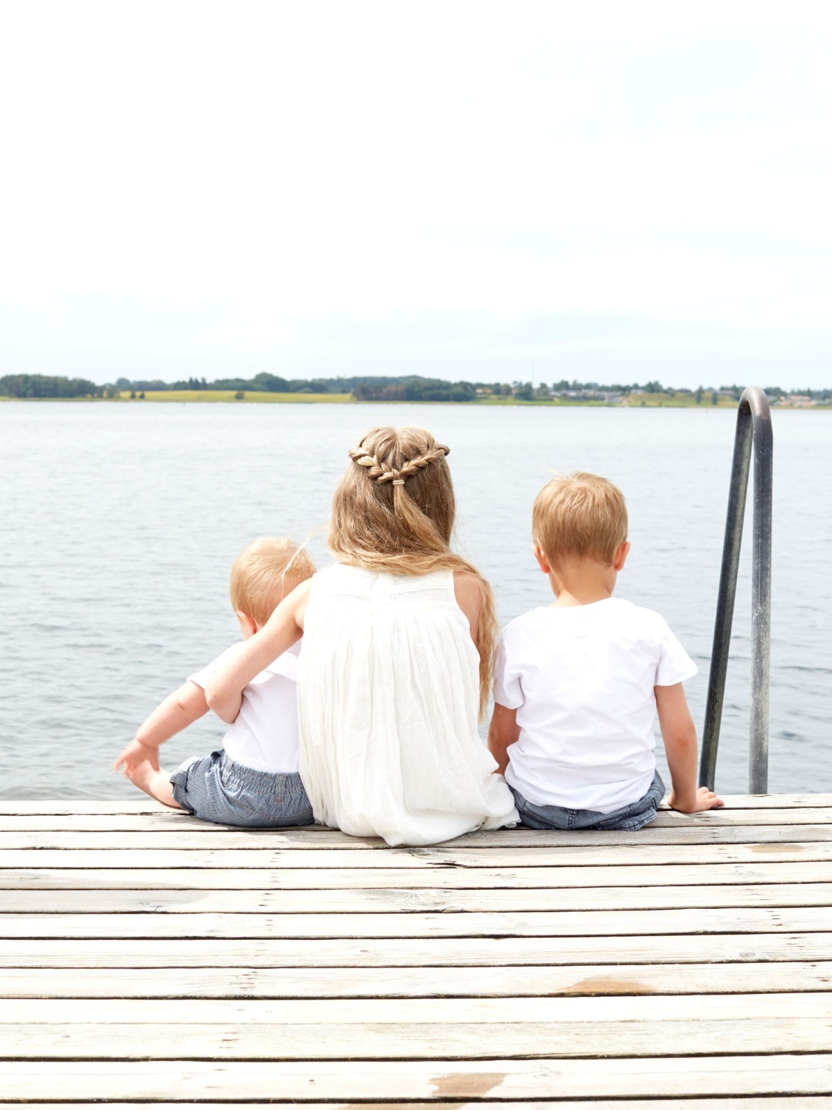Kids sitting on a dock by the water